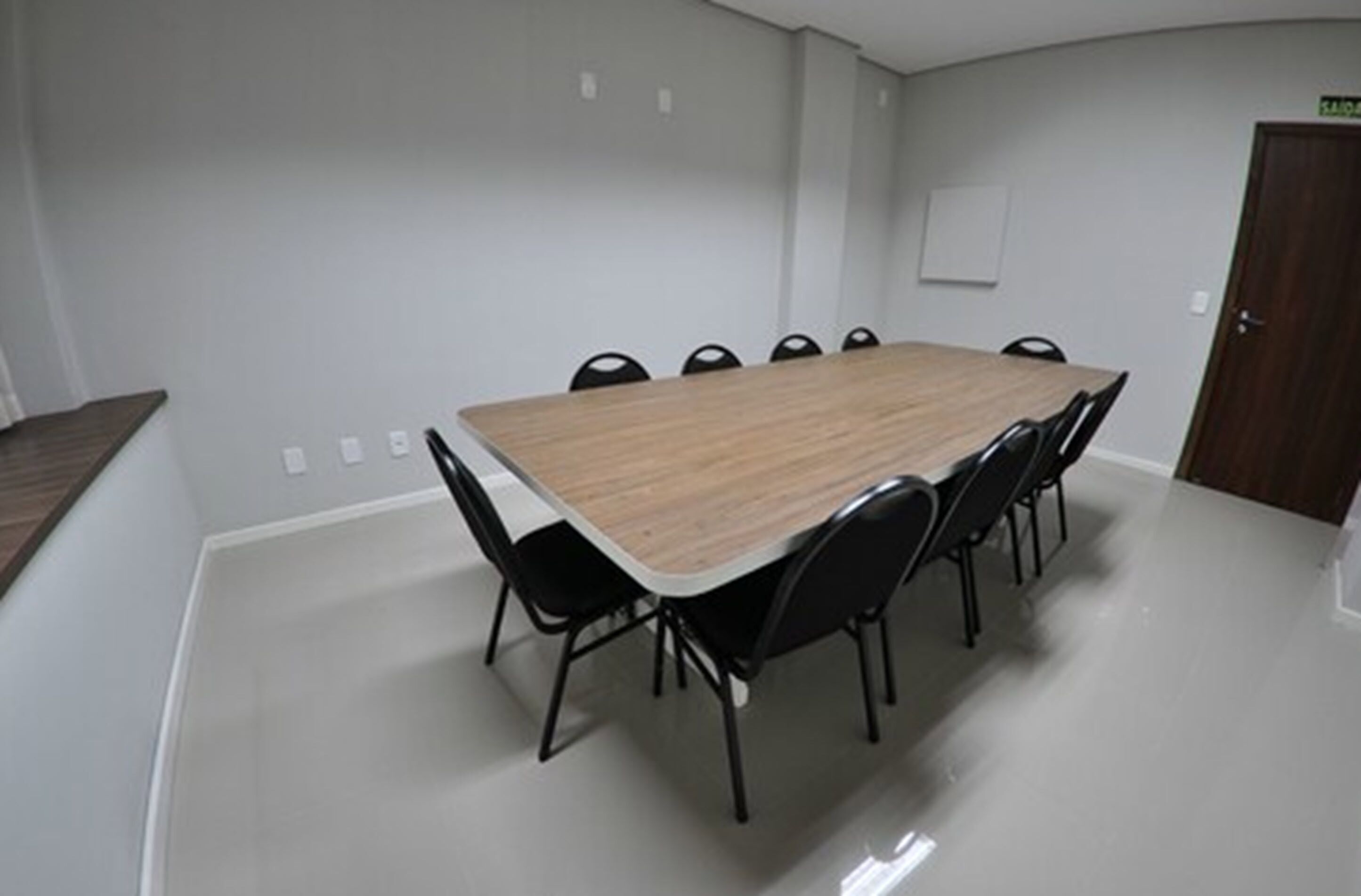 Una sala de conferencias con una mesa rectangular y sillas negras.