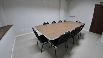 Una sala de conferencias con una mesa rectangular y sillas negras.