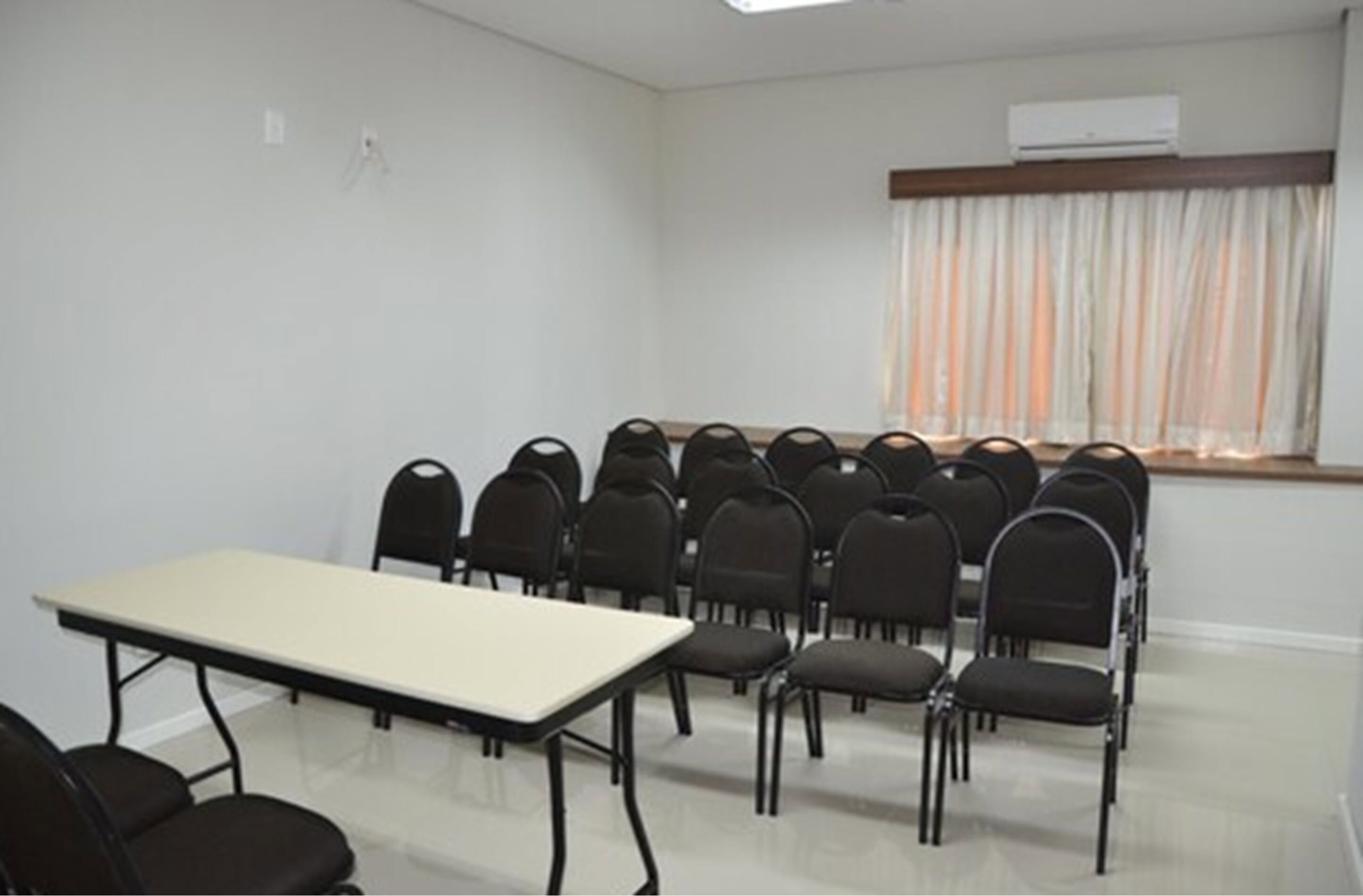 A conference room with a long table and rows of chairs.