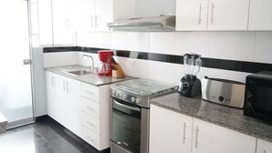Eine moderne Küche mit weißen Schränken, einem Gasherd, einem Toaster und einem Mixer.