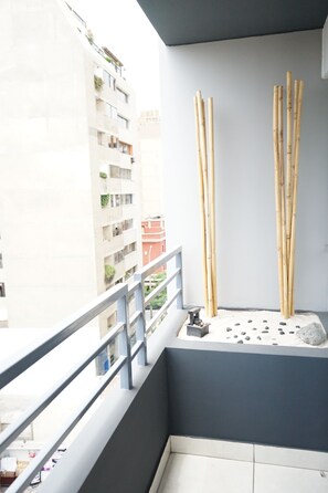 Un balcon donnant sur un immeuble, avec une balustrade et des tiges de bambou.