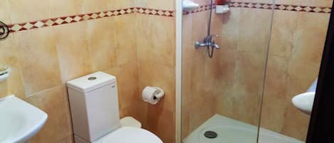 Et badeværelse med toilet, bruser og håndvask.