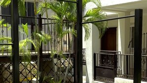 Une cour intérieure avec un palmier, une clôture en métal et un bâtiment doté de balcons.