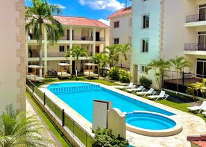 A hotel with a swimming pool, multiple balconies, and palm trees. - Punta Cana Seven Beaches (Punta Cana)