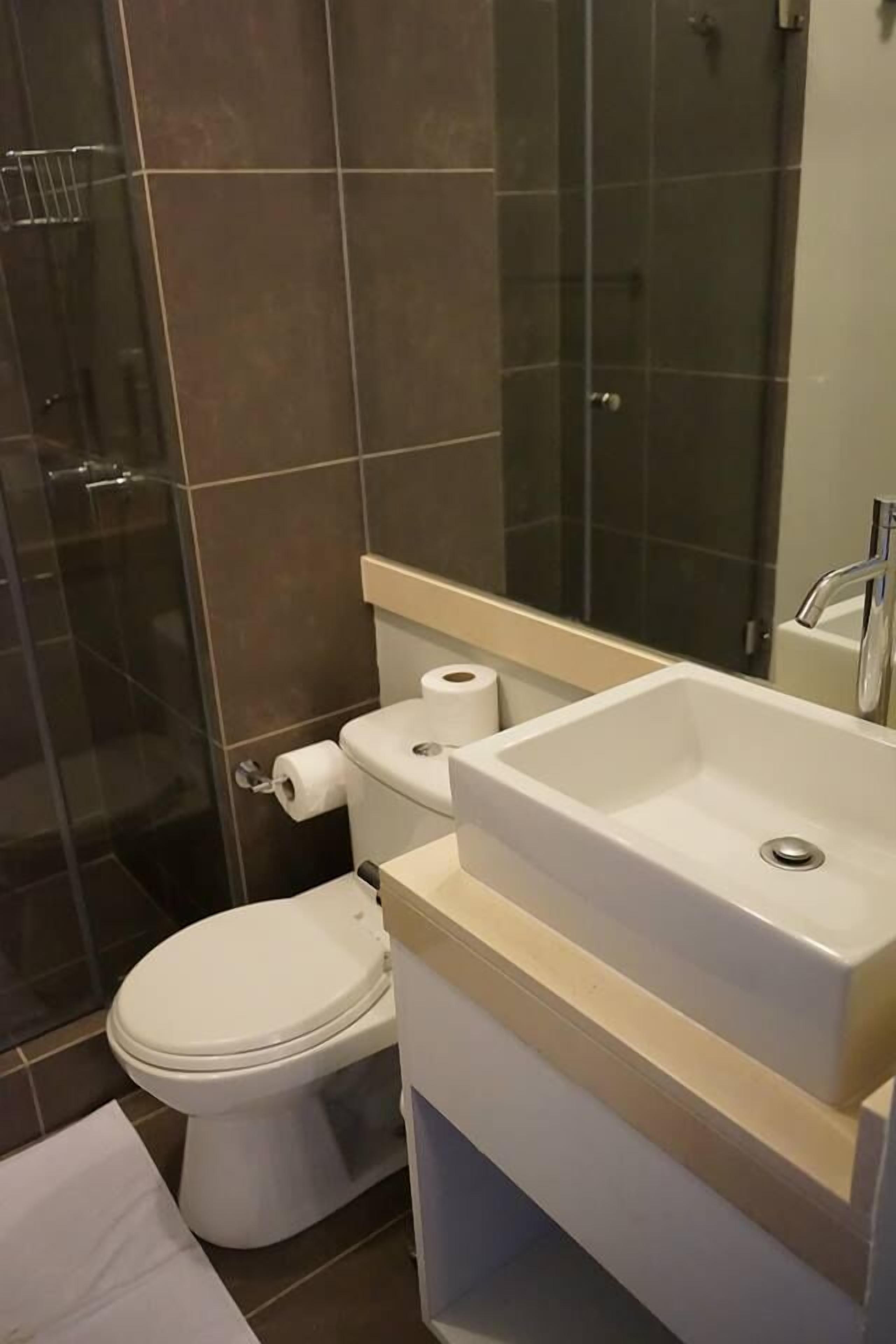A bathroom with a toilet, sink, and shower area.