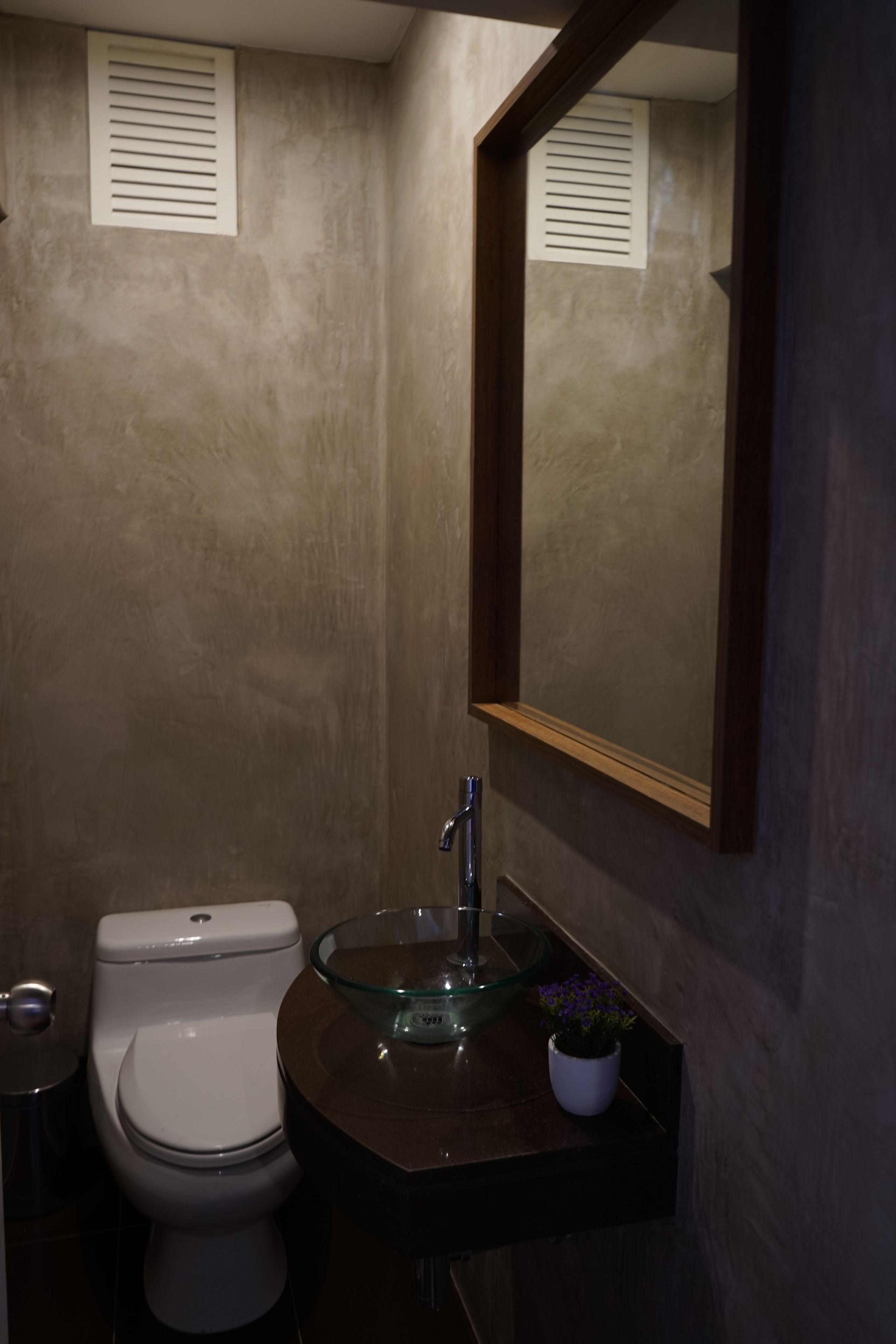 Ein Badezimmer mit Toilette, einem Glaswaschbecken und einem Spiegel.