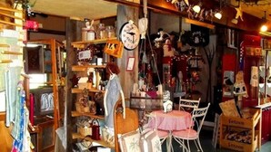 A cozy, cluttered shop with shelves of various items, a small table with chairs, and a clock on the wall. - Heritage Inn (Richfield Springs)