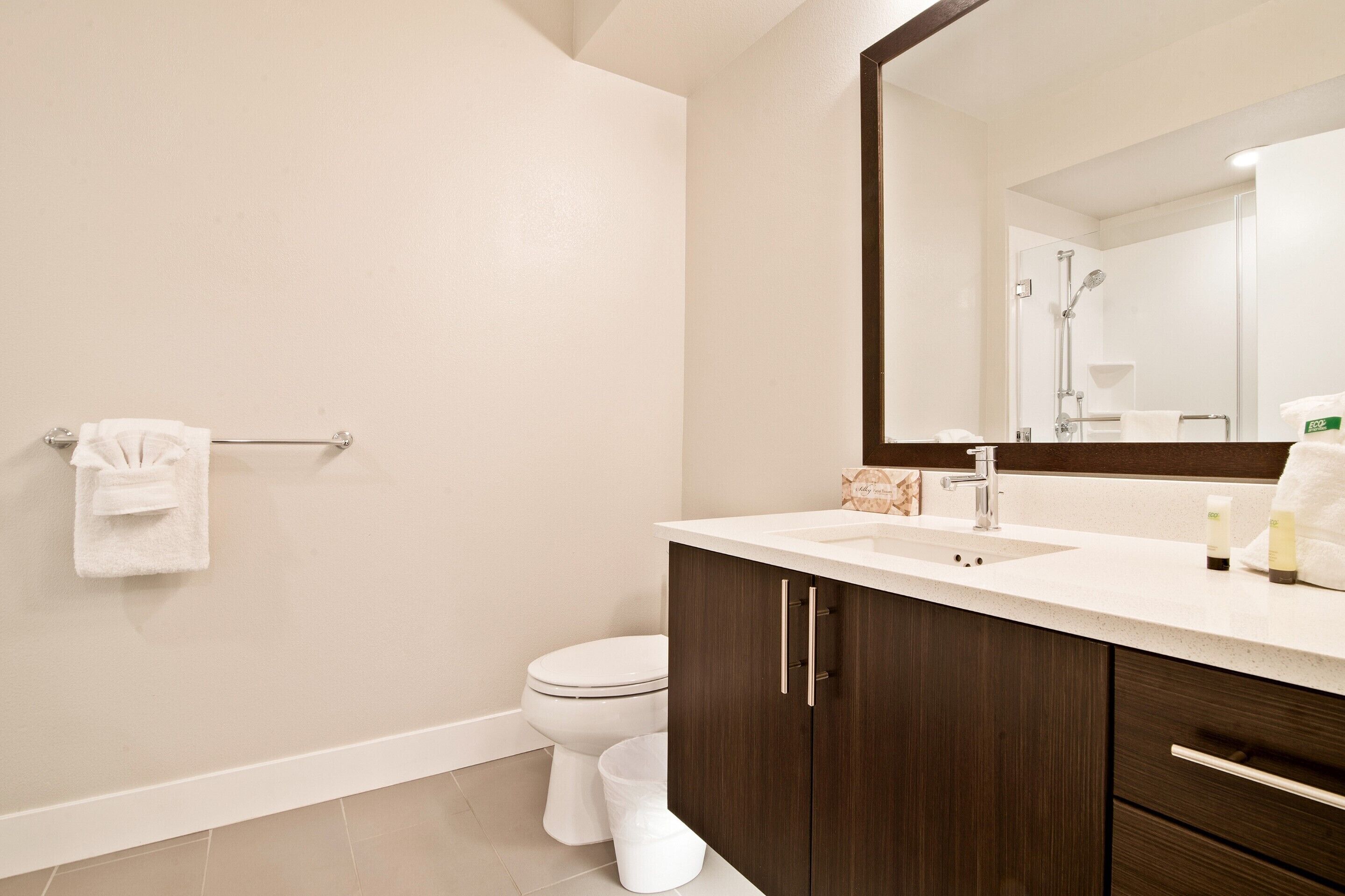 Een moderne badkamer met een wit toilet, een wastafel en een grote spiegel.