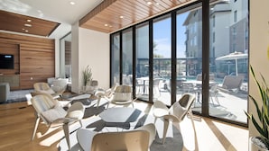 A modern lounge area with a large window overlooking a pool and outdoor seating. - Global Luxury Suites at Mountain View (Mountain View)