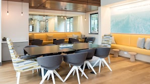 A modern meeting room with a large table, grey chairs, a yellow sofa, and a large window. - Global Luxury Suites at Mountain View (Mountain View)