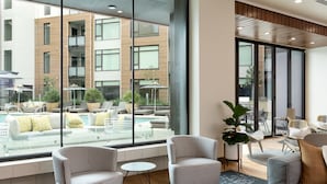 A modern hotel lobby with large windows, a pool view, and contemporary furniture. - Global Luxury Suites at Mountain View (Mountain View)