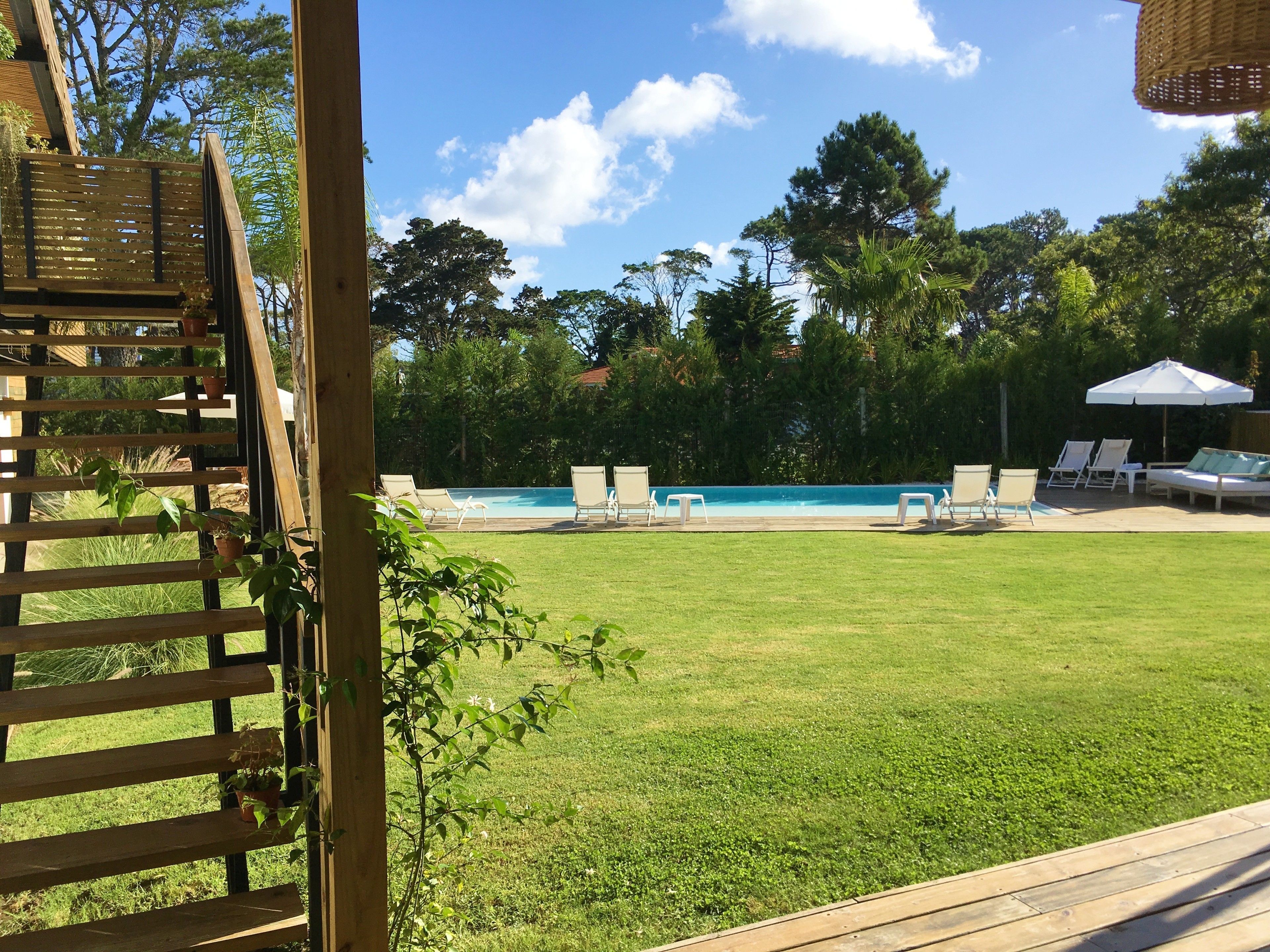 Zona junto a la piscina con vista despejada, rodeada de césped y árboles.