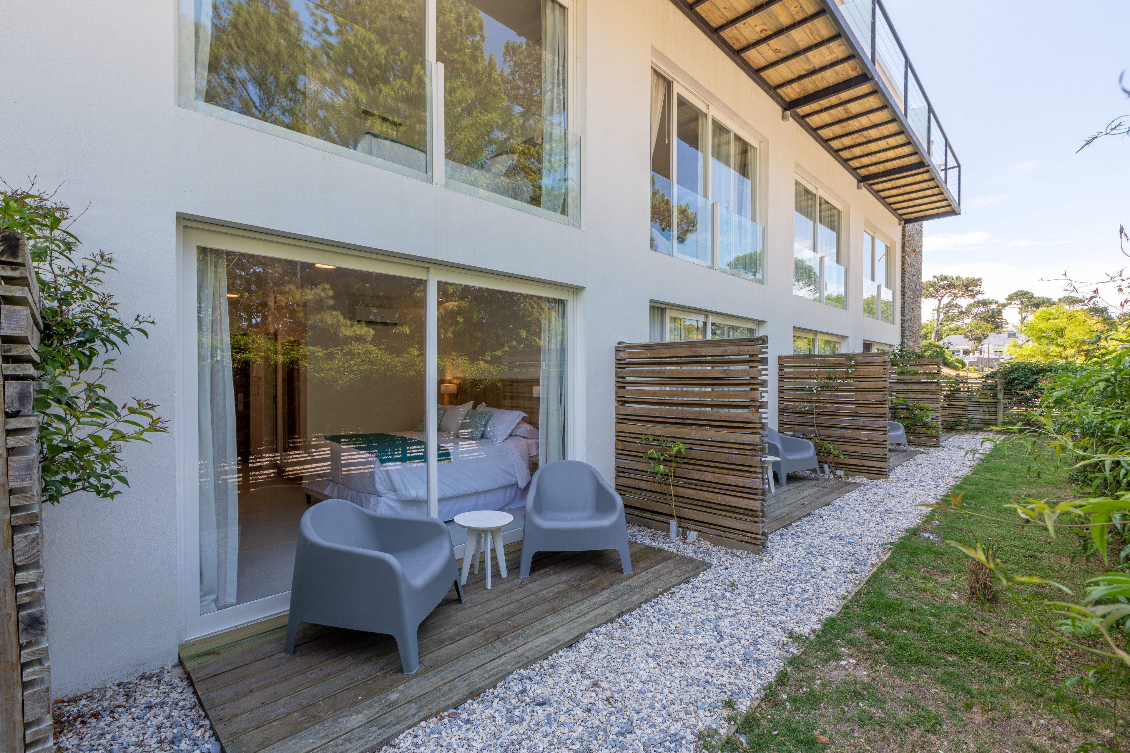 A modern house with a patio area featuring a wooden deck, outdoor seating, and a view of the interior.