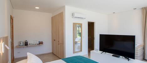 Una habitación de hotel moderna con una cama, un televisor, un espejo y un estante con artículos de aseo.