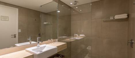 Un baño moderno con dos lavamanos, una cabina de ducha de vidrio y un espejo grande.