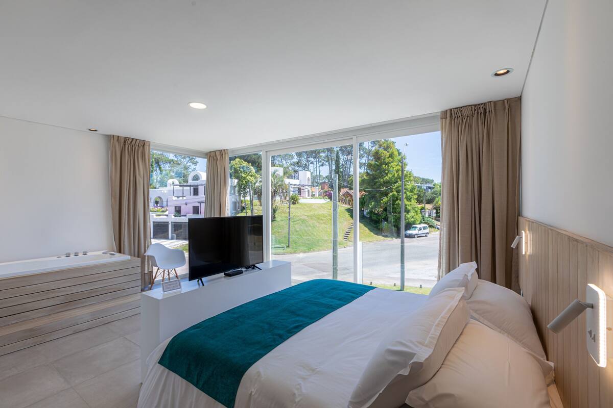 Een moderne hotelkamer met een groot bed, een televisie op een bureau en uitzicht naar buiten.