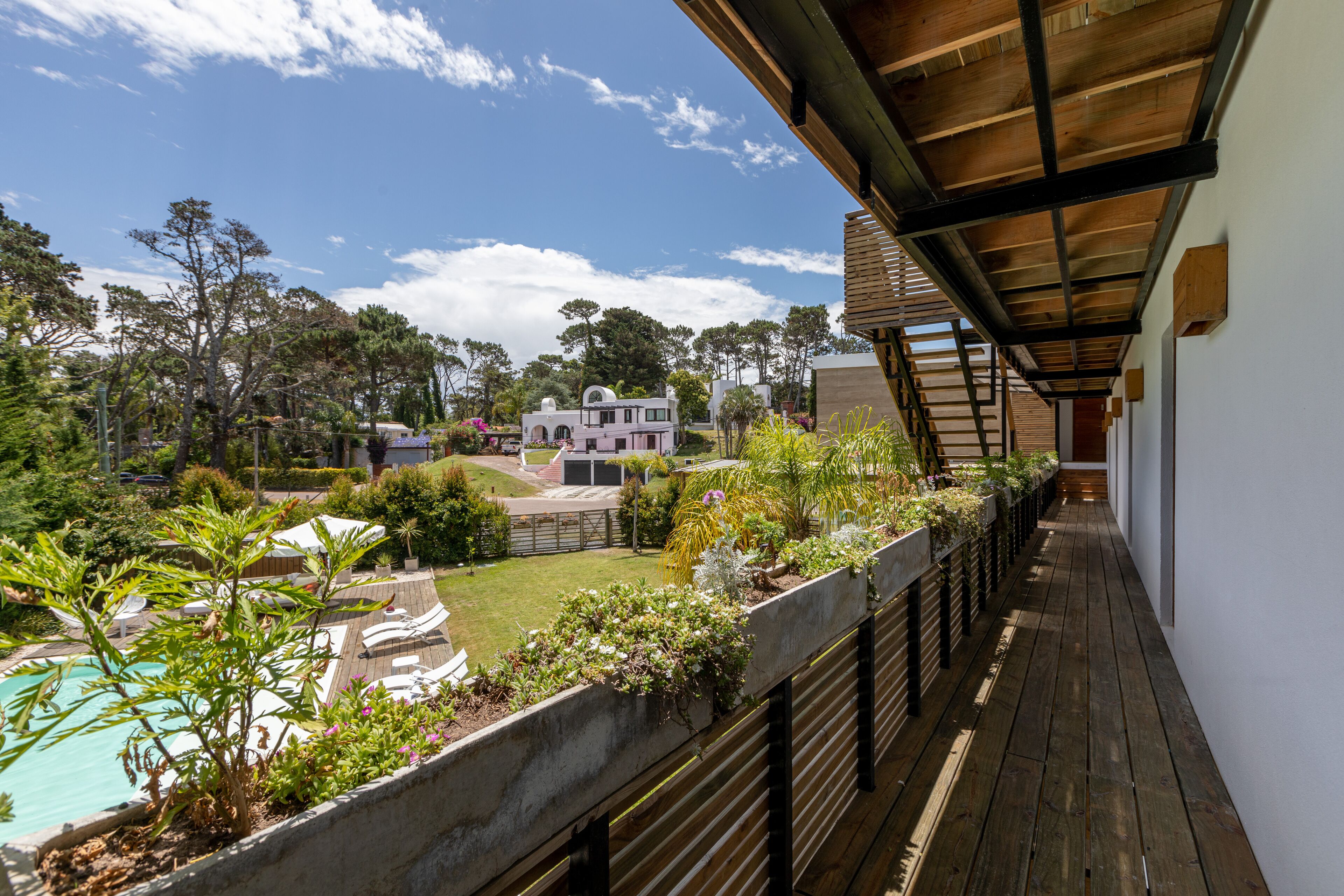 A balcony with a view of a swimming pool, garden, and neighboring houses.
