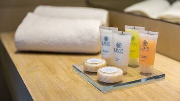 A wooden tray with four toiletry items and a folded towel on a wooden surface.