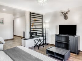 Una sala de estar moderna con televisor, cabeza de venado decorativa y una escalera con diseño geométrico en la pared.