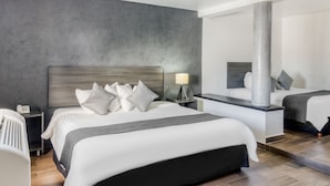 A modern hotel room with a large bed, bedside tables, a mirror, and a chandelier. - VN Hotel (Monterrey)