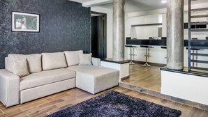 A modern living room with a sectional sofa, a black and white photograph on the wall, and a chandelier. - VN Hotel (Monterrey)