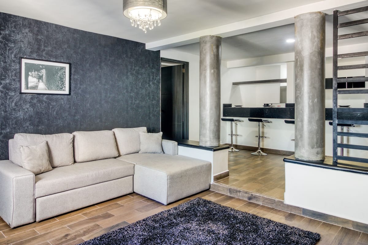 Una sala de estar moderna con un sofá modular, una fotografía blanco y negro en la pared y un candelabro.