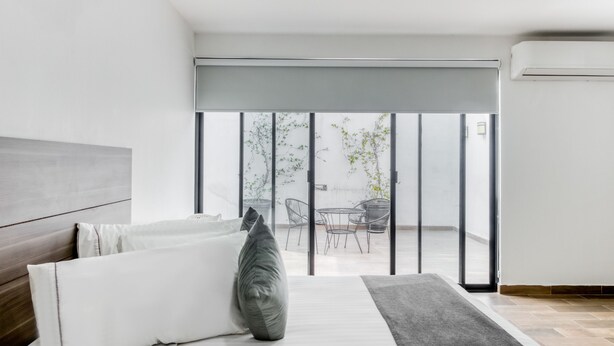 A modern bedroom with a bed, a large window, and a view of the outside balcony. - VN Hotel (Monterrey)