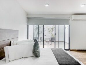 A modern bedroom with a bed, a large window, and a view of the outside balcony. - VN Hotel (Monterrey)