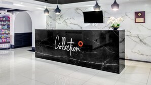 A reception desk with a marble countertop and a large screen above it. - VN Hotel (Monterrey)