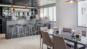 A modern kitchen with a central island, bar stools, and pendant lighting. - VN Hotel (Monterrey)