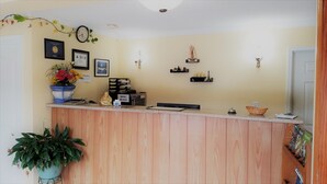 A reception area with a wooden counter, a clock, framed certificates, and a small plant.