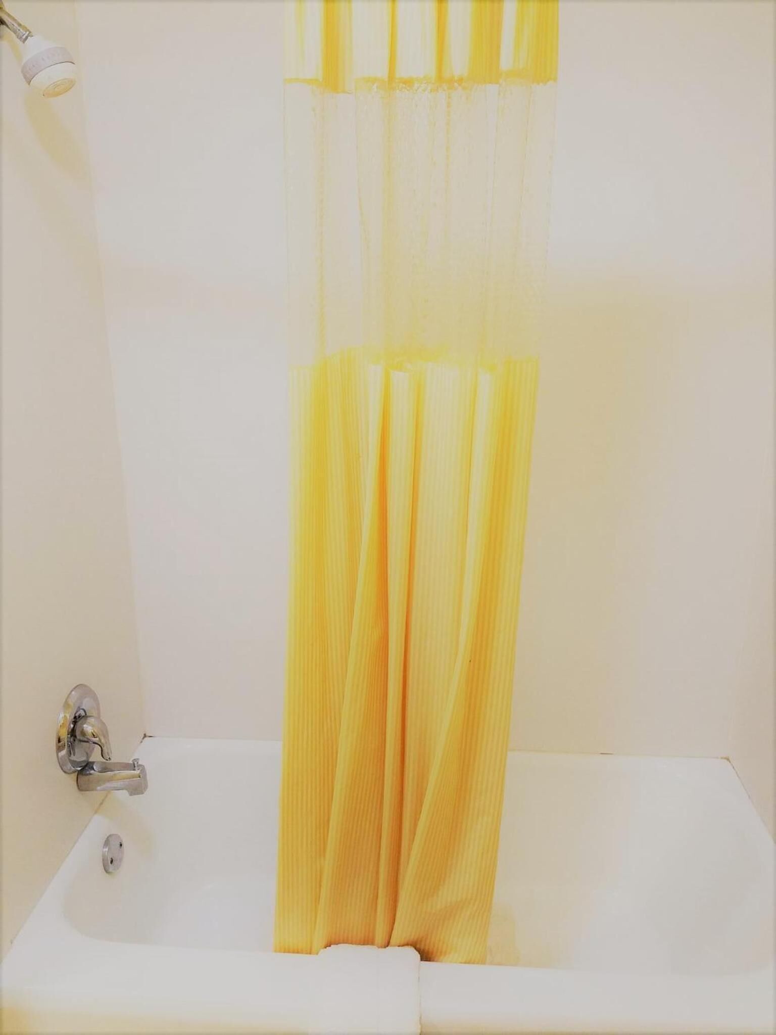 Une salle de bain avec une baignoire, un rideau de douche et un robinet.