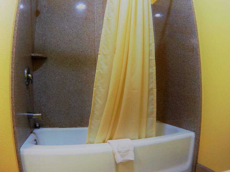 A bathroom with a bathtub, shower curtain, and toilet.