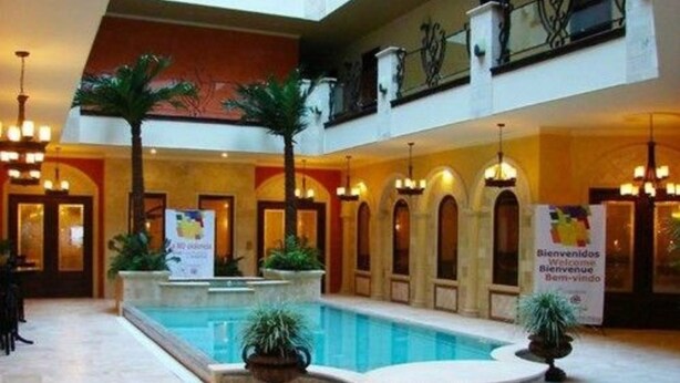 A hotel lobby with a central pool, multiple arches, and potted plants. - Hotel Gran Mediterraneo (San Pedro Sula)