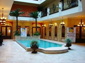 A hotel lobby with a central pool, multiple arches, and potted plants. - Hotel Gran Mediterraneo (San Pedro Sula)