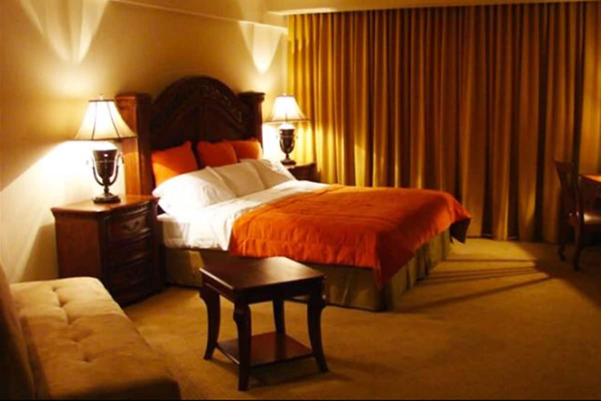 Ein Hotelzimmer mit einem großen Bett, zwei Nachttischen mit Lampen, einem kleinen Tisch und einem Sessel.