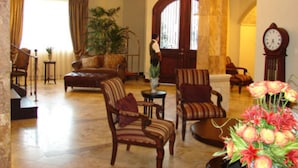 A spacious lobby with a sofa, armchairs, a coffee table, and a large potted plant. - Hotel Gran Mediterraneo (San Pedro Sula)