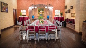 A long dining table with red tablecloths and white chairs, set in a room with brick walls and wooden floors. - Hotel Gran Mediterraneo (San Pedro Sula)