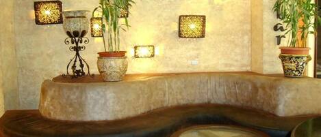 Un rincón acogedor con un banco curvo, plantas en macetas e iluminación en la pared.