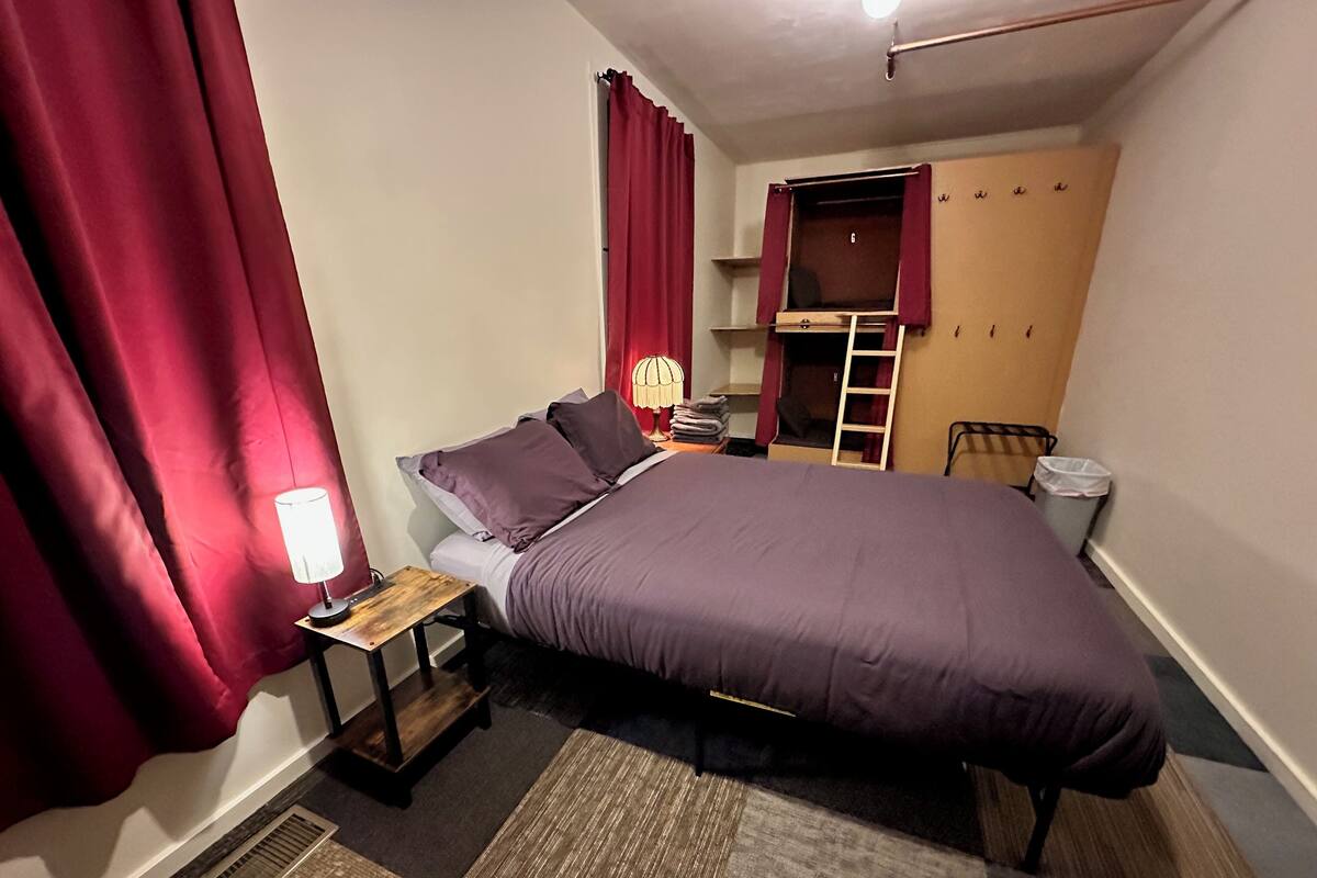 Une chambre à coucher comprenant un lit, une table de chevet, une lampe, une armoire et une chaise.