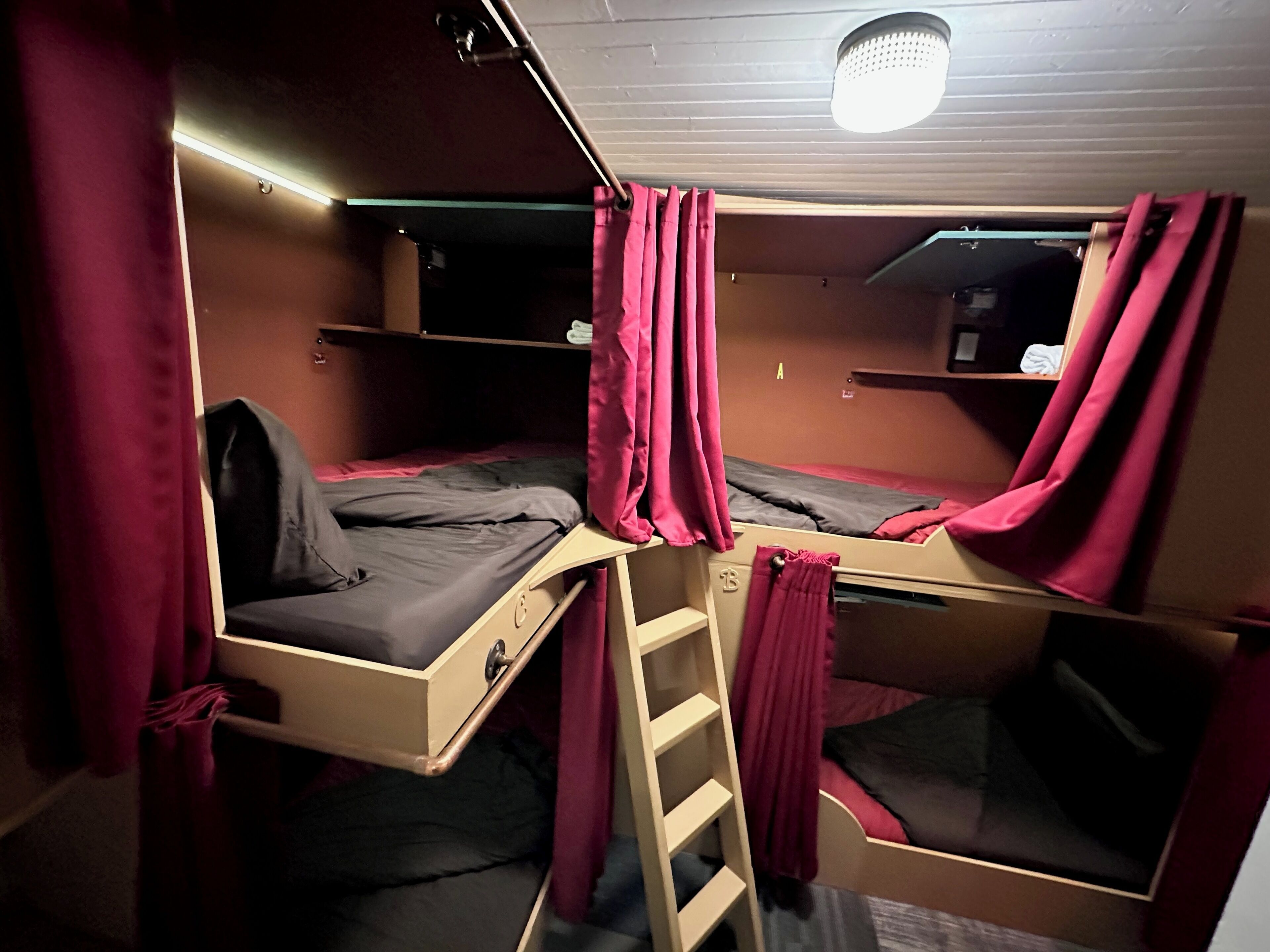 A bunk bed room with a ladder, a desk, and a shelf.