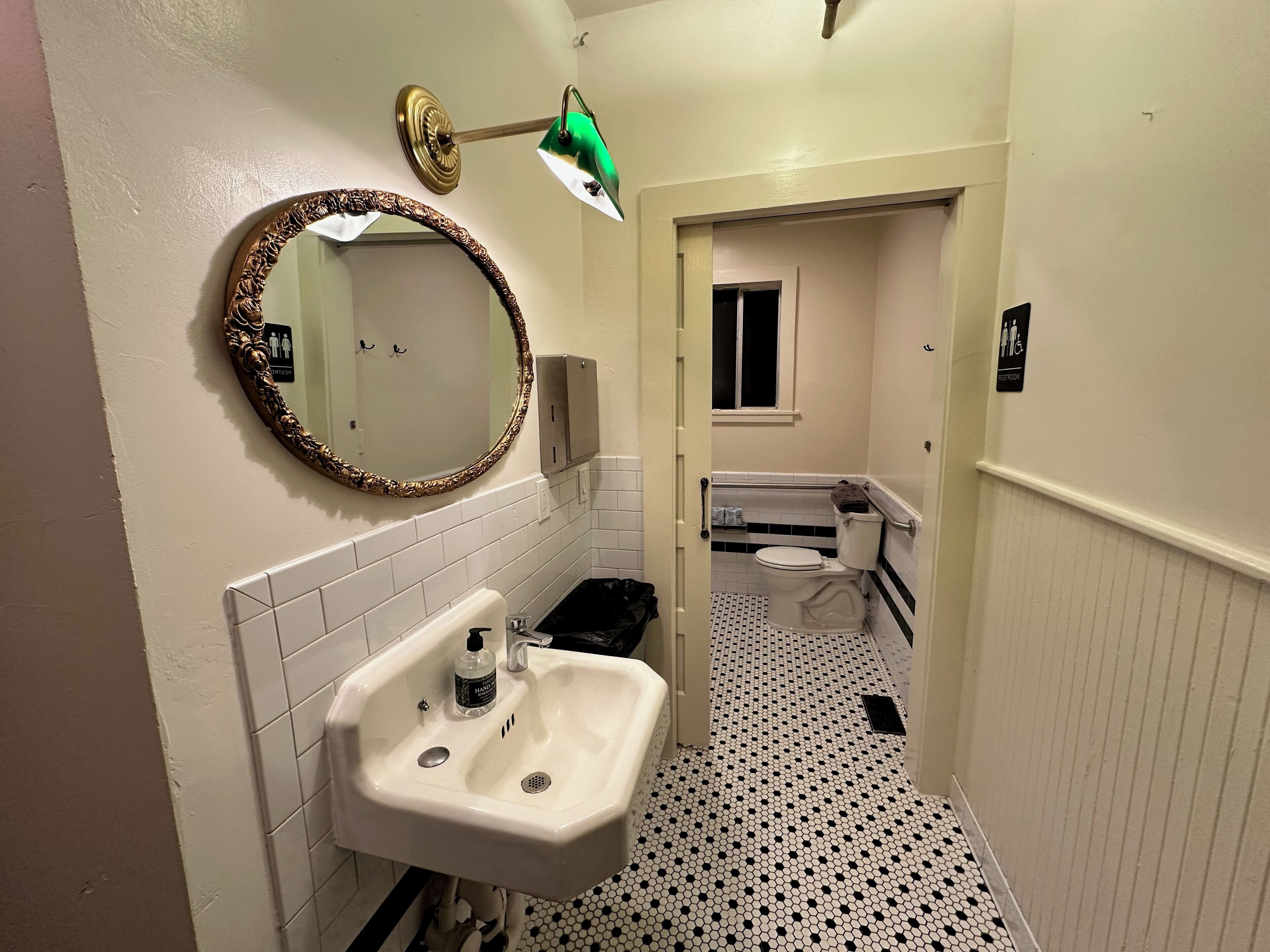 Un baño estrecho con un lavamanos blanco, un espejo y un inodoro.