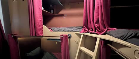 A bunk bed room with a ladder, a desk, and a small shelf.