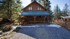 A cabin with a metal roof, wooden walls, and a gravel driveway. - 44mbr - Hot Tub- Pets Ok - Wifi - Bbq - Sleeps 8 2 Bedroom Home by RedAwning (Deming)