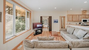 A modern living room with a large TV, a sofa, and a wooden coffee table. - 70mbr- Hot Tub - Bbq - Wi-fi - Pets Ok - Sleeps 8 3 Bedroom Home by RedAwning (Deming)