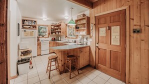 A kitchen with wooden cabinets, a central island with stools, a refrigerator, and a stove. - 32mbr - Bbq - Pets Ok - Wood Stove - Sleeps 7 3 Bedroom Home by RedAwning (Deming)
