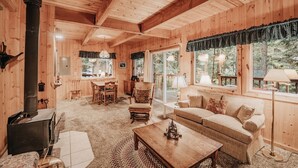 A cozy cabin interior with a dining area, a sofa, and a fireplace. - 32mbr - Bbq - Pets Ok - Wood Stove - Sleeps 7 3 Bedroom Home by RedAwning (Deming)
