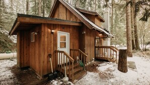 Eine Holzhütte mit Veranda, einer Tür und einer Treppe, die zu einer Terrasse führt.