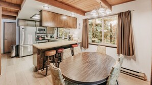 Eine moderne Küche mit Holzschränken, einem Edelstahlkühlschrank und einer zentralen Kochinsel mit Sitzgelegenheiten.
