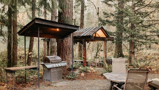 An outdoor grill area with a wooden table and chairs, surrounded by trees. - 03mbh -12-bdrm - 3.5-bath - Wifi - Pets Ok - Sleeps 26 12 Bedroom Home by RedAwning (Deming)